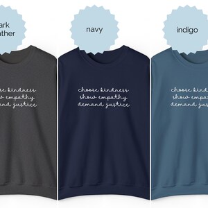 May include: Three crewneck sweatshirts in dark heather, navy, and indigo colors. Each sweatshirt features the white text "choose kindness, show empathy, demand justice" printed in a cursive script font across the center of the chest area.