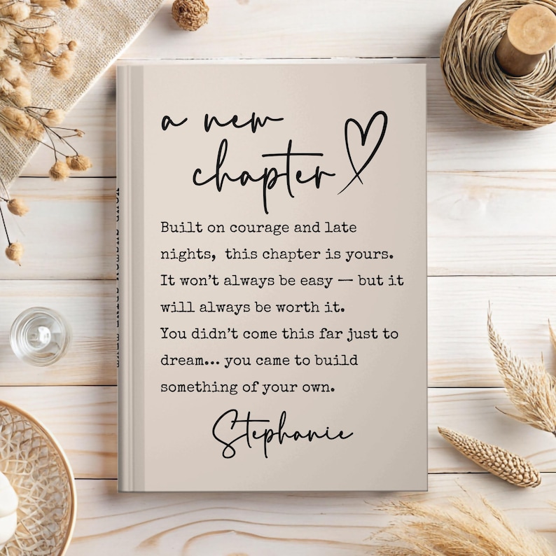 May include: A beige hardcover journal with the words "a new chapter" and a heart symbol in black script. The journal includes inspirational text about courage and building something of your own, signed "Stephanie".