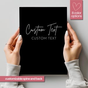 May include: A black notebook with the text "Custom Text" in white lettering. The notebook has a customizable spine and back. There are 8 color options available.