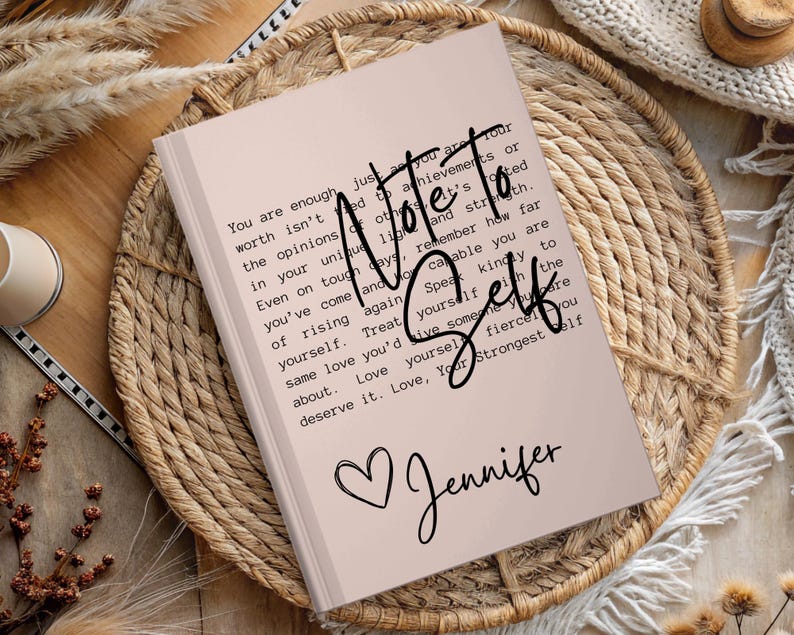May include: A pink notebook with the text "Note to Self" in black lettering. The notebook has a heart and the name "Jennifer" written in black cursive.