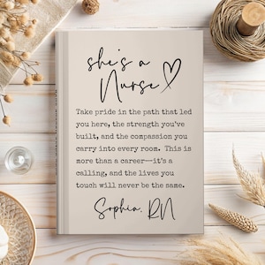 May include: A beige notebook with the text "she's a Nurse" and a heart symbol. The notebook contains a message about nursing, signed "Sophia, RN". The notebook is on a light wooden surface with decorative elements.