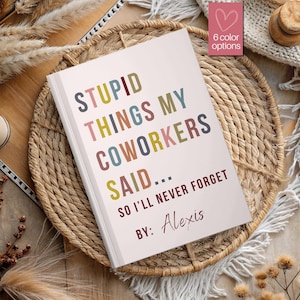 May include: A white notebook with the text "STUPID THINGS MY COWORKERS SAID... SO I'LL NEVER FORGET BY: Alexis" in various colors. The notebook is on a woven basket. A small pink heart with "6 color options" is in the upper right corner.