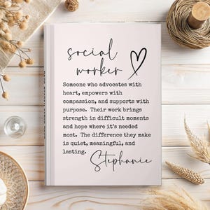 May include: A white notebook with the words "social worker" and a heart symbol in black script. The text below describes the role of a social worker. The name "Stephanie" is written at the bottom in cursive.