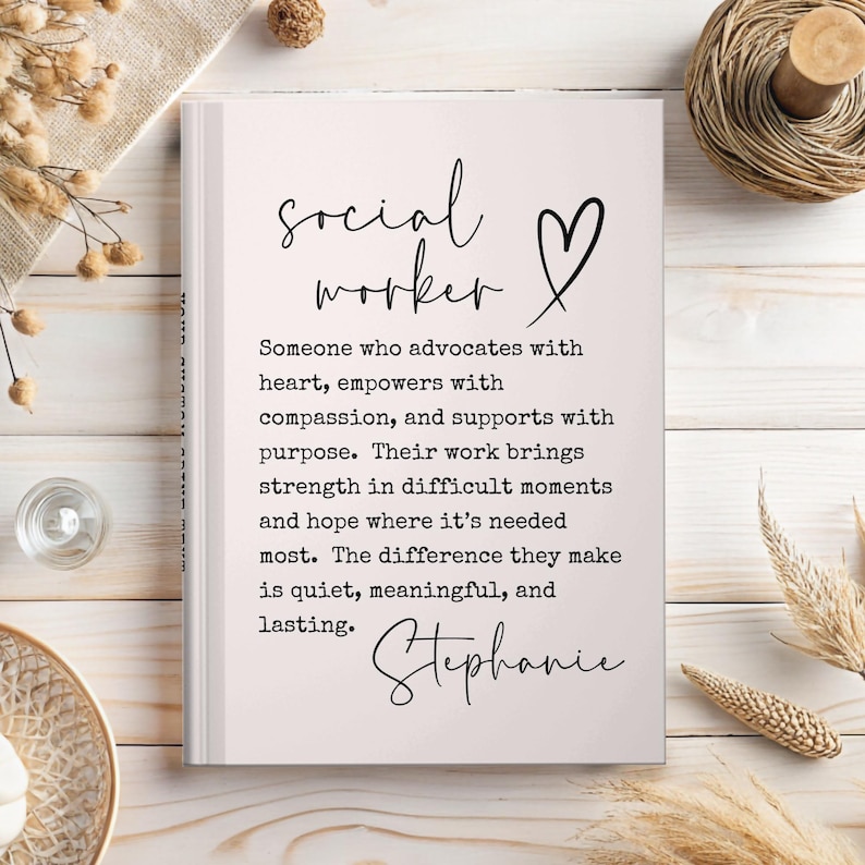 May include: A white notebook with the words "social worker" and a heart symbol in black script. The text below describes the role of a social worker. The name "Stephanie" is written at the bottom in cursive.