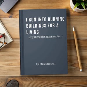 May include: A hardcover book with a dark blue cover, titled "I Run Into Burning Buildings For A Living." The text "...my therapist has questions" and the author's name, Mike Brown, are also visible. The book is on a wooden surface.