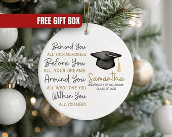May include: White ceramic graduation ornament with gold string, featuring a black mortarboard and the text "Behind You, All Your Memories, Before You, All Your Dreams, Around You, All Who Love You, Within You, All You Need." Includes name, university, and class year.