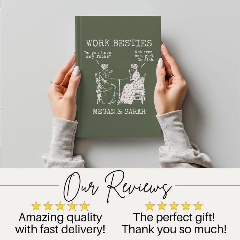 May include: A dark olive green hardcover book with white text that reads WORK BESTIES, MEGAN & SARAH, and dialogue bubbles stating Do you have any fucks? and Not even one, girl. Go fish. above a line drawing of two people sitting at a table.