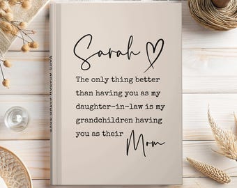 May include: A beige journal with the name "Sarah" and a heart symbol in black script. The text reads, "The only thing better than having you as my daughter-in-law is my grandchildren having you as their Mom."