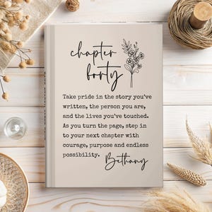 May include: A hardcover book with the words "chapter forty" in elegant script. The book's cover is a light beige color, with floral accents and inspirational text. The name "Bethany" is also written on the cover.