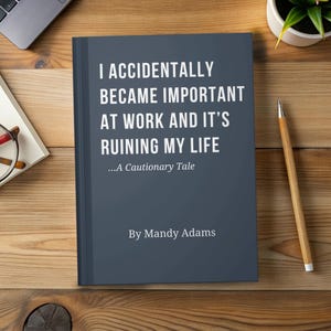 May include: A dark blue hardcover book with white text that reads I ACCIDENTALLY BECAME IMPORTANT AT WORK AND IT'S RUINING MY LIFE ...A Cautionary Tale By Mandy Adams. The book is positioned on a wooden surface next to a wooden pencil.