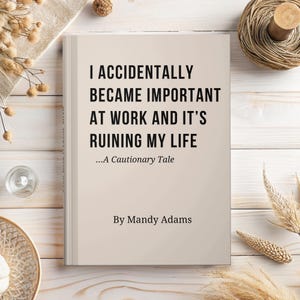 May include: A hardback book with a light beige cover featuring the black text: I ACCIDENTALLY BECAME IMPORTANT AT WORK AND IT'S RUINING MY LIFE ...A Cautionary Tale By Mandy Adams. The book is positioned centrally on a light wooden surface.