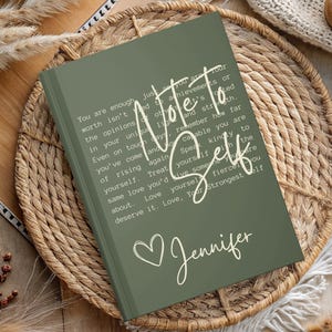 May include: A green journal with the text "Note to Self" in white lettering. The journal has a white heart and the name "Jennifer" written in white cursive.