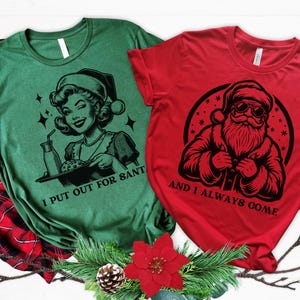 May include: Two Christmas themed t-shirts. The green shirt features a woman with a tray of cookies and the text "I put out for Santa". The red shirt features Santa Claus with the text "And I always come".