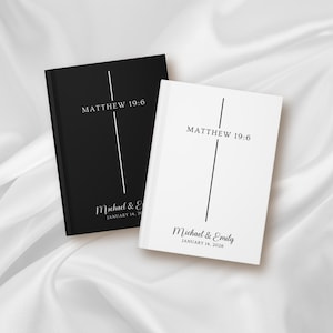 May include: Two hardcover books, one black and one white, with the text "MATTHEW 19:6" and names and a date. The black book has "Michael &" and "JANUARY 14, 20" printed on it. The white book has "Michael & Emily" and "JANUARY 14, 2026" printed on it.