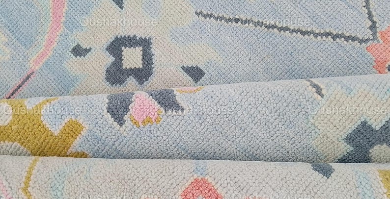 May include: Close-up of a blue, pink, and yellow patterned rug with a soft, textured surface.