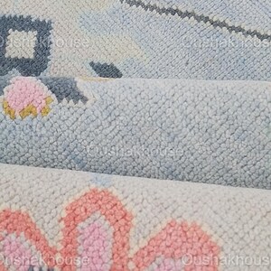 May include: Close-up of a light blue and pink patterned rug with a floral design. The rug is made of a soft, fluffy material.