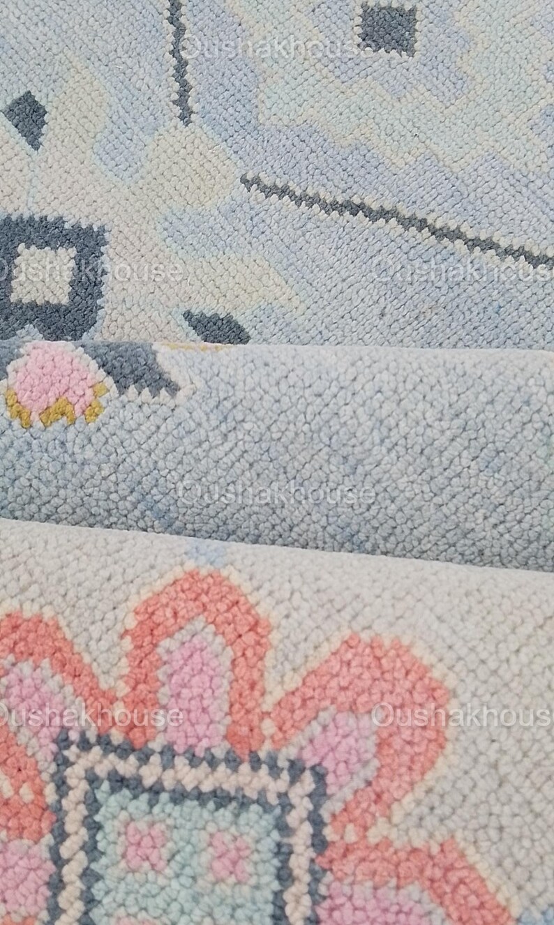 May include: Close-up of a light blue and pink patterned rug with a floral design. The rug is made of a soft, fluffy material.
