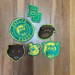 May include: A collection of Baylor Bears patches in green, yellow, and brown. The patches feature the Baylor logo, a bear paw, and the letters "BU". The patches are embroidered and have a vintage look.