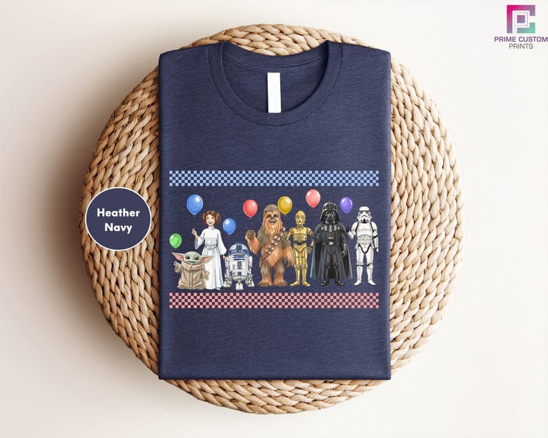 A navy blue t-shirt with a graphic design featuring various characters from popular media, including a baby star, a robot, a character with a balloon, and a character in a stormtrooper outfit.