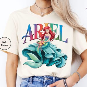a woman wearing a white ariel t - shirt with the word ariel on it