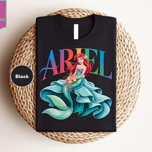 a black ariel t - shirt sitting on top of a woven basket