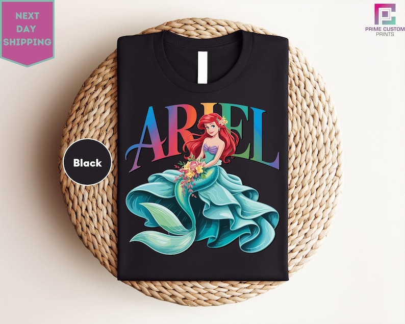a black ariel t - shirt sitting on top of a woven basket