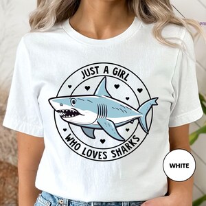 a woman wearing a white shirt with a shark on it