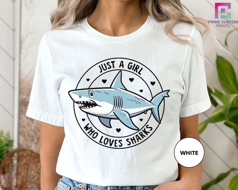 a woman wearing a white shirt with a shark on it