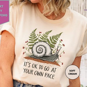 a woman wearing a t - shirt that says it's ok to go at