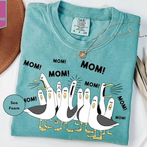 a woman wearing a t - shirt with three geese saying mom, mom, mom