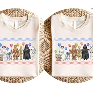 two white t-shirts with a graphic design of various Star Wars characters, including Darth Vader, Chewbacca, and Yoda, along with balloons.