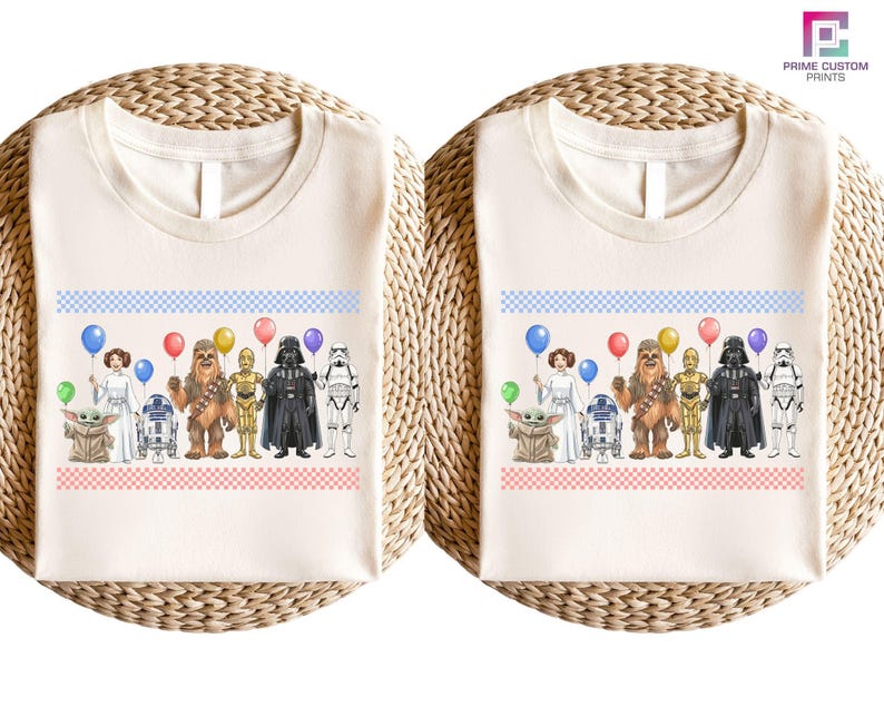 two white t-shirts with a graphic design of various Star Wars characters, including Darth Vader, Chewbacca, and Yoda, along with balloons.