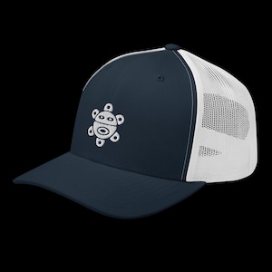 May include: Navy blue trucker hat with a white mesh back and a curved brim. The hat features a white embroidered design of a stylized turtle on the front panel. The hat is a classic accessory for casual wear.