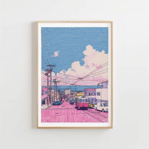May include: A framed art print depicting a street scene with a pink road and buildings. The sky is blue with fluffy white clouds. A red and yellow trolley car is on the tracks. Power lines and utility poles are visible.
