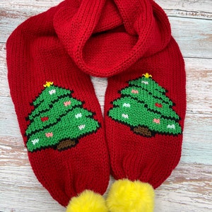 May include: Red knitted scarf with two yellow pom-poms and green Christmas tree designs.