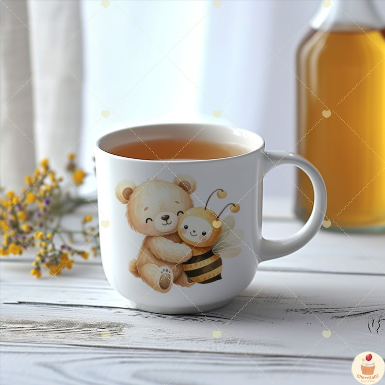 May include: White ceramic mug with a brown bear and a yellow bee illustration. The bear is hugging the bee. The mug is filled with a light brown liquid.