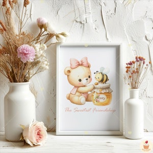 May include: A white frame with a pink and yellow illustration of a teddy bear holding a jar of honey with a bee on top. The text "The Sweetest Friendships" is below the illustration.