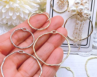 May include: A collection of gold and silver-toned hoop earring components. Some hoops have a hammered texture. Two pairs of earrings are displayed, one with clear crystals and the other with white pearls.