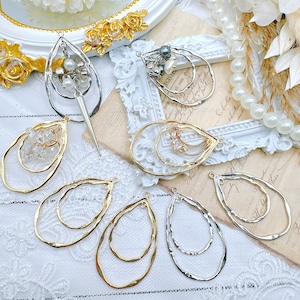 May include: Assortment of gold and silver teardrop-shaped earrings with intricate designs. Some earrings feature multiple layers and decorative elements, including beads and crystals.