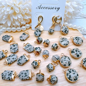 May include: A collection of 20 dalmatian jasper stone pendants with gold-toned accents. The pendants are in various shapes, including round, square, and rectangular. The stones are a mix of black and white with a speckled pattern.