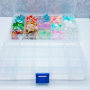 May include: A clear plastic organizer with a blue clasp, filled with colorful craft beads. The beads are various shapes and colors, including turquoise, red, gold, purple, pink, and white. The organizer has multiple compartments for easy storage and organization.
