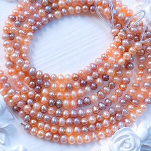 May include: Strands of freshwater pearls in shades of peach, pink, and mauve. The pearls are strung together, showcasing their natural, irregular shapes. The image is a close-up, highlighting the luster and color variations of the pearls, perfect for jewelry making.