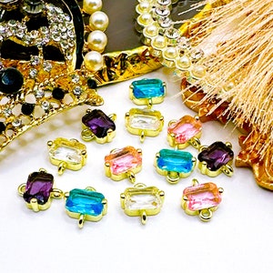 May include: Assortment of colorful rectangular glass charms with gold metal accents. The charms have a variety of colors including pink, blue, purple, and clear.