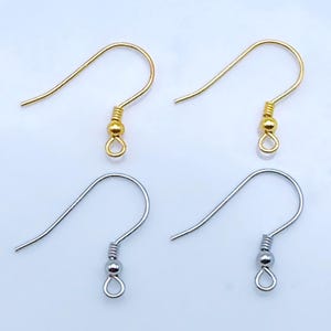 May include: Four metal earring hooks arranged in two rows. The top row features two gold-toned fishhook-style earring wires, while the bottom row contains two silver-toned fishhook-style earring wires. Each hook includes a small coil and a bead.