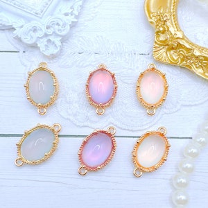 May include: Six oval-shaped, iridescent glass cabochons with gold-tone metal settings. Each cabochon is surrounded by a decorative border and has two jump rings for attaching to jewelry.
