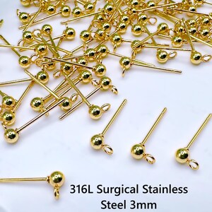 May include: A collection of gold-colored earring posts with a ball and loop design. The posts are made of 316L surgical stainless steel and are 3mm in size. The earrings are scattered on a white surface.