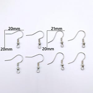May include: A collection of silver-colored earring hooks, each with a curved design and a small ball at the bottom. The hooks are approximately 20mm to 21mm in length, ideal for crafting earrings.