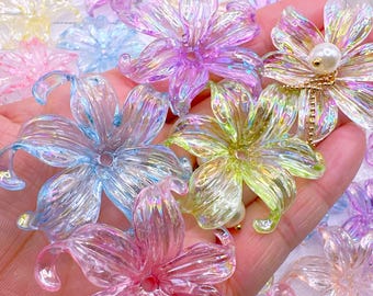 Può includere: Una collezione di abbellimenti a forma di fiore traslucidi e iridescenti in vari colori, tra cui rosa, blu, giallo e viola. Alcuni fiori hanno un centro di perla e dettagli di catena dorata. Questi elementi decorativi sono ideali per l'artigianato.