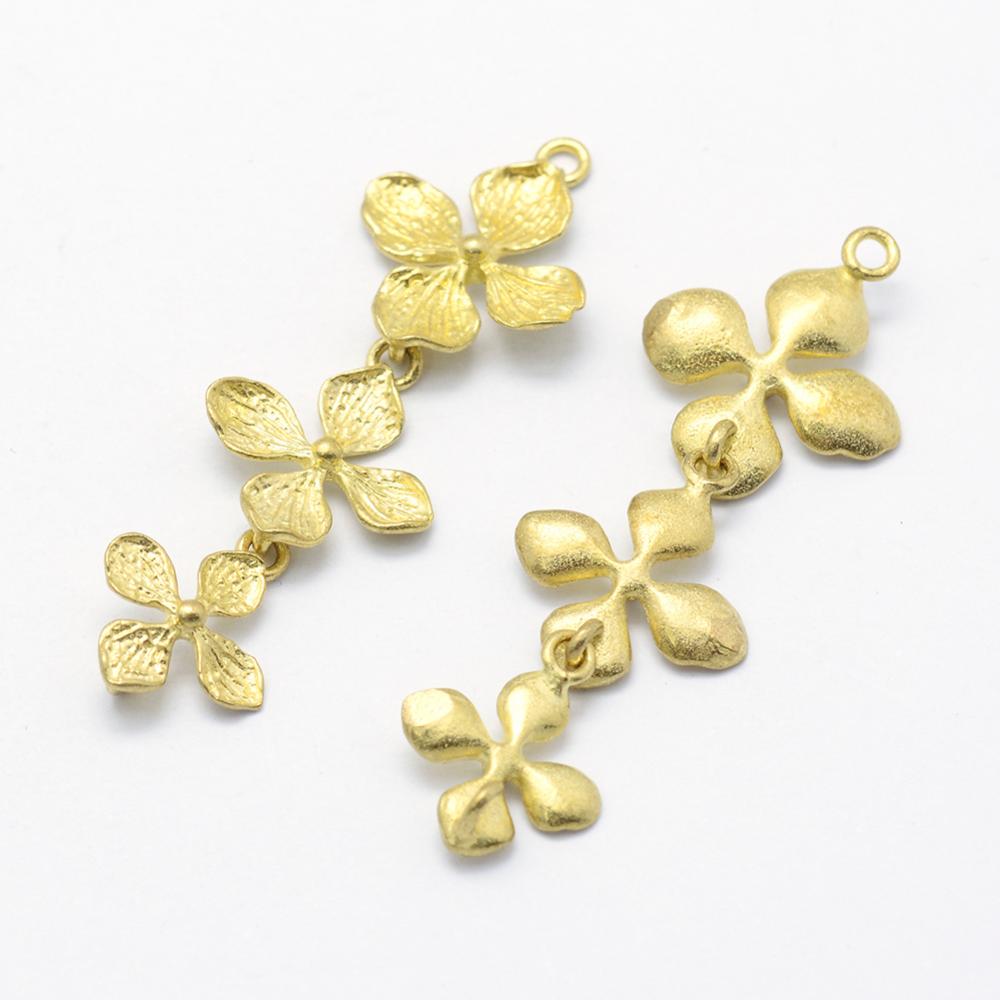 May include: Two gold-toned metal flower charms with a chain connecting each flower. The charms are in the shape of a four-petal flower.