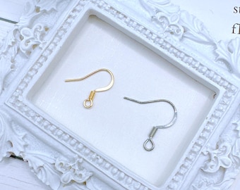 May include: Two earring hooks, one gold and one silver, on a white background. The hooks are made of metal and have a spring closure.
